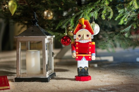 Nutcracker statue standing in front of decorated Christmas tree