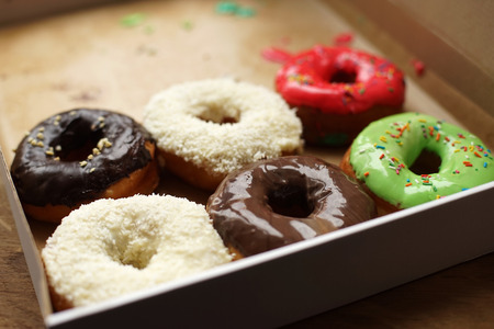 Colorful donuts in box, half-empty box, coconut toppingの写真素材