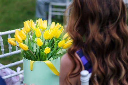 Bouquet of yellow tulips in the hands. A photo from the back.
