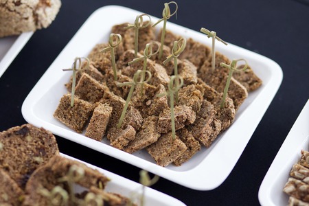 Bread cut into little squares for tasting, with the skewers laid out on a white plateの写真素材
