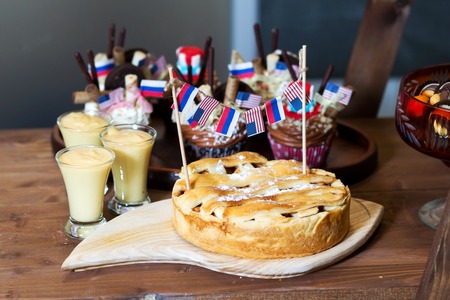 Apple pie decorated with flags of America and Russia. Stands on a wooden butcher in the background cupcakes and mousse cupsの写真素材