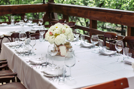 Floral arrangement of white flowers at the wedding table. Beautiful wooden chairs. The bouquet is to decorate with books.の写真素材
