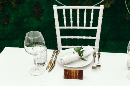 Table for guests on the veranda, white tablecloths and napkins in the background of green Park.の写真素材