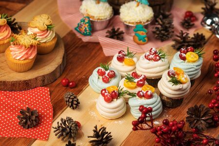 Christmas table with sweets. Decorated with pine cones and tablecloths, lined with cupcakes, meringue and gingerbread.の写真素材