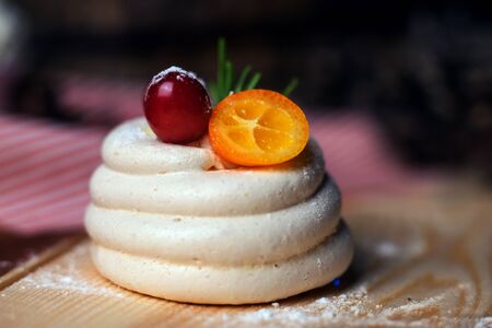 Meringue with berries and a slice of kumquat on top. Studio light.の写真素材