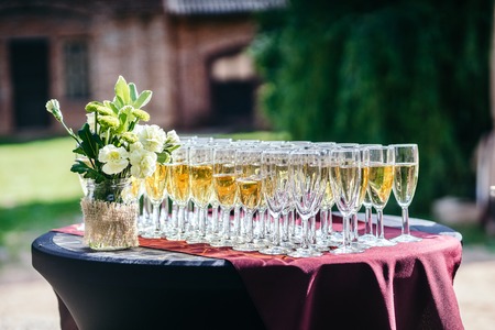 Glasses with champagne on a beautiful black table, in the Park in the summer. Sunny weather.の写真素材