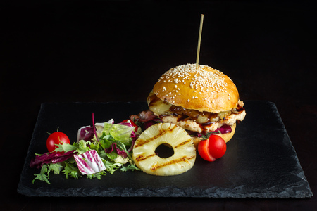 Hamburger with pineapple lies on a black slate surface-2の写真素材
