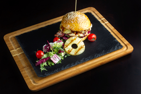 Hamburger with pineapple lies on a black slate surface-3の写真素材