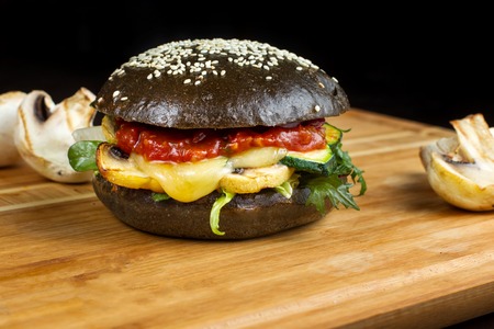 Black burgers with meat, cucumber and green lettuce on the wooden.の写真素材