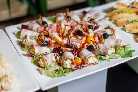 Rolls of bacon are laid out on a white plate.の写真素材
