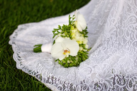 Wedding bouquet of white lilies lies on a dressの写真素材