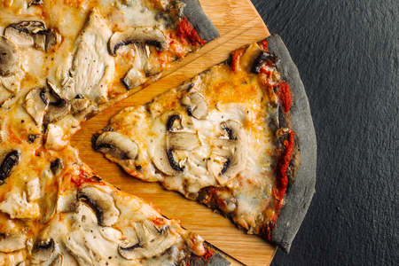 Pizza with champignons and chicken breast on black dough.の写真素材
