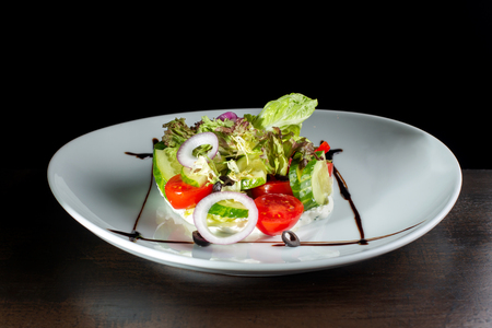 Salad with cheese and fresh vegetables on white plate.の写真素材