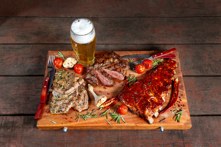 Grilled meat, ribs and vegetables on rustic wooden table. Delicious meat platter. With beer.の写真素材
