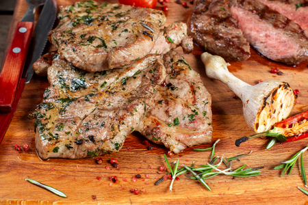 Grilled meat, ribs and vegetables on rustic wooden table. Fried meat, close-up.の写真素材