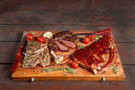 Grilled meat, ribs and vegetables on rustic wooden table. Delicious meat platter.の写真素材