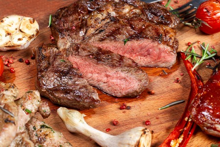 Grilled meat, ribs and vegetables on rustic wooden table. Steak weak roast, close-up.の写真素材