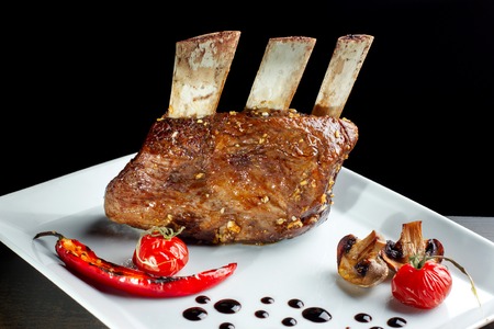 Delicious barbecued ribs seasoned served with mushrooms on a white plate.の写真素材