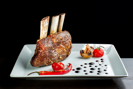 Delicious barbecued ribs seasoned served with mushrooms on a white plate.の写真素材