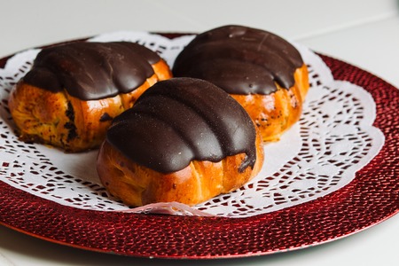 Three buns with poppy seeds and chocolate icing on a plate.の写真素材