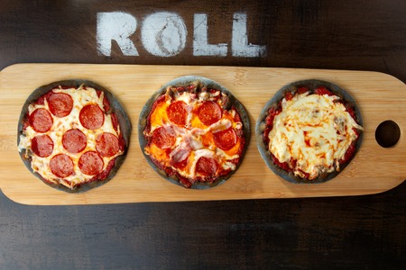 Creative pizza on black dough, three pieces on the board.の写真素材