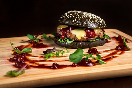Hamburger with cowberry sauce, tasty and appetizing with a black bun and cheese.の写真素材