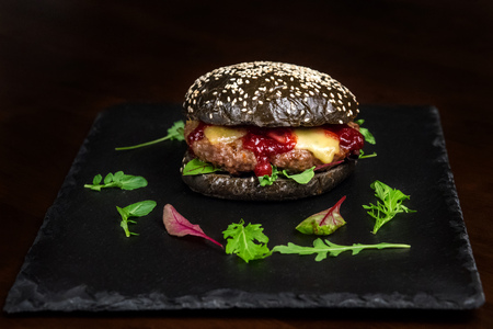 Hamburger with cowberry sauce, tasty and appetizing with a black bun and cheese.の写真素材