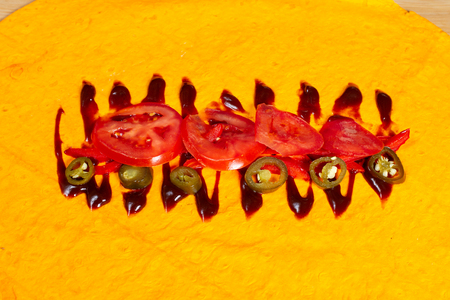 Yellow tortilla stuffed with donut. Sauce, jalapeno, tomatoes, bell peppers.の写真素材
