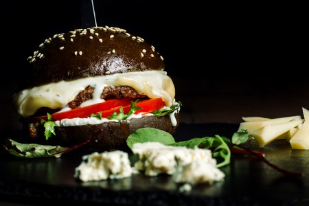 Black Burger with Cheese and salad on black slate.の写真素材