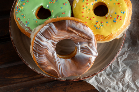 Three Stacked doughnuts on plate. Chocolate, Yellow, Green.の写真素材