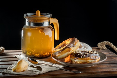 Beautiful composition. In the foreground are donuts on a plate, the warm light from the kettle falls on them.の写真素材