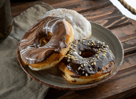 Three donuts on a design plate, backlight. Stands on a wooden tray.の写真素材