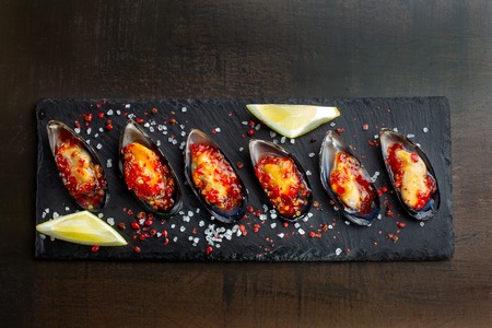 Six oysters. Fresh oysters are laid out on black slate, coarse salt is sprinkled around. Seafood.の写真素材