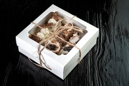Choux pastry, with cream and chocolate on a black background in a gift box.の写真素材