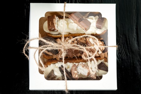 Choux pastry, with cream and chocolate on a black background in a gift box.の写真素材