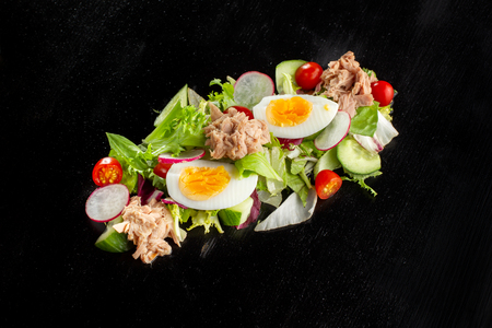 Salad with chicken, egg and tomato scattered black board.の写真素材
