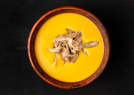 Pumpkin soup with Chiken in a clay plate on black background.の写真素材