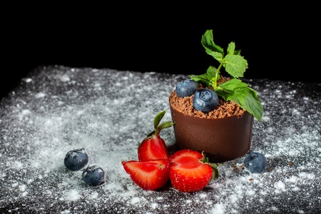 Chocolate dessert in a pot in the form of homemade flower on a black slate covered with powdered sugar.の写真素材