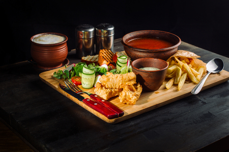 Lunch on a wooden board. Soup, chicken breast, salad and sauce-2.の写真素材