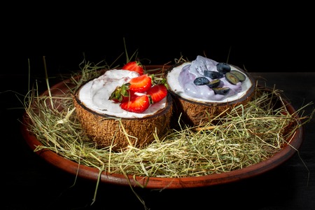 Strawberry and Blueberry ice cream in coconut halves with fresh berries.の写真素材