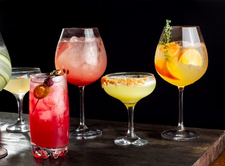 Four alcoholic cocktails with orange slices, ice, watermelon slices, cherries, pears and cucumbers.の写真素材