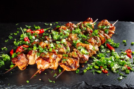 Grilled meat skewers, shish kebab on black slate. They lie close to each other.の写真素材