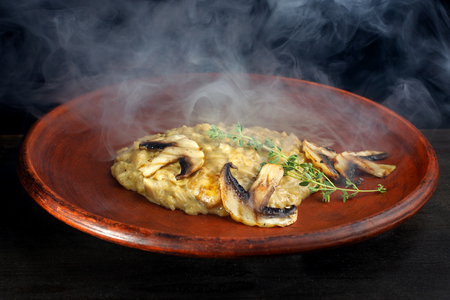 Wheat porridge with mushrooms on a black background in a clay plate.の写真素材