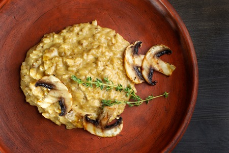 Wheat porridge with mushrooms on a black background in a clay plate.の写真素材