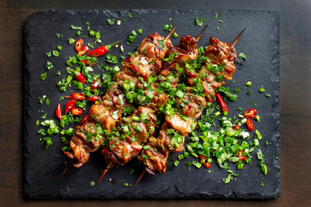 Grilled meat skewers, shish kebab on black slate. They lie close to each other.の写真素材