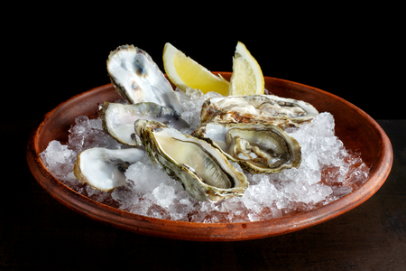 Fresh open oysters and lemon laid out on ice-2.の写真素材