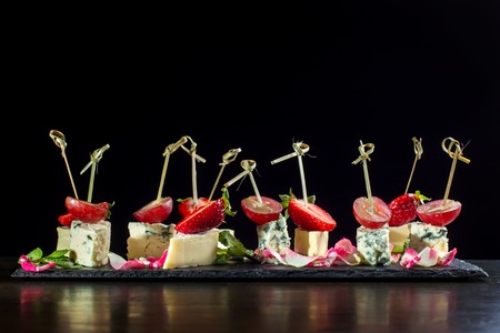 Cheese plates served with strawberry and grapes on black slate-2.の写真素材