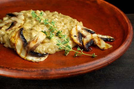 Wheat porridge with mushrooms on a black background in a clay plate.の写真素材