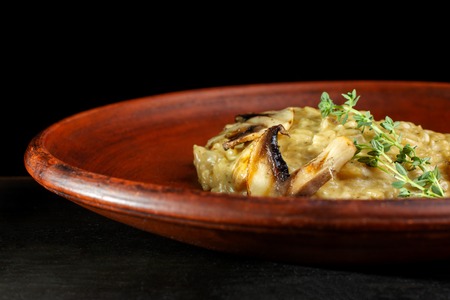 Wheat porridge with mushrooms on a black background in a clay plate.の写真素材