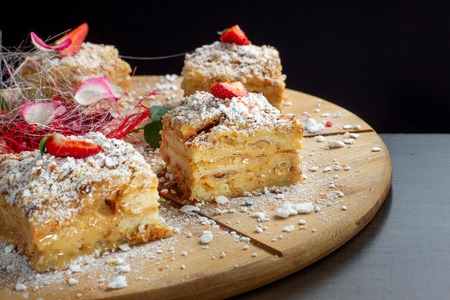 Four piece of cake Napoleon on wooden tray. Russian cuisine, layered cake with pastry cream.の写真素材